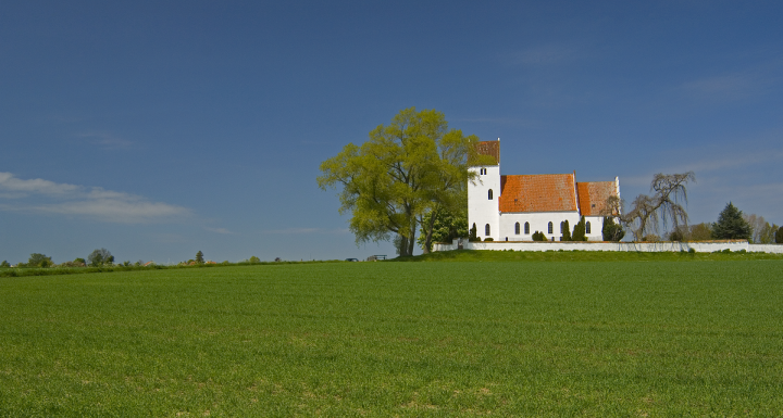 Foto af dansk kirke med mark foran