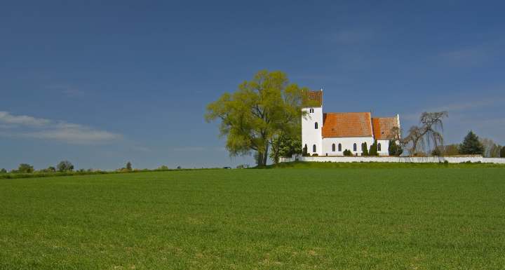 Foto af dansk kirke med mark foran 